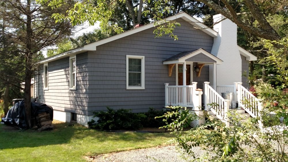 Same house after remodel with gray shingle siding and new porch